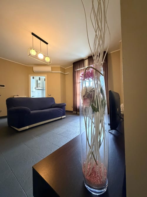 Modern living room in Cinelli Apartment, Vercelli with dark blue sofa, pendant lighting, and decorative plant arrangement