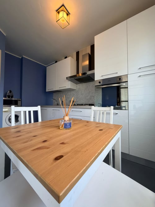 Modern kitchen-dining area at Cinelli Apartment in Vercelli with wooden table, white cabinetry, blue accent walls, and