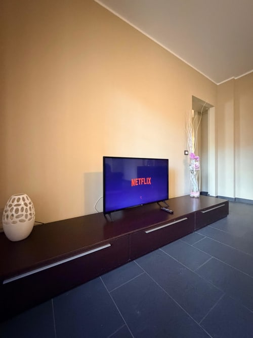 Modern living room at Cinelli Apartment in Vercelli with flat-screen TV showing Netflix, black media console, white