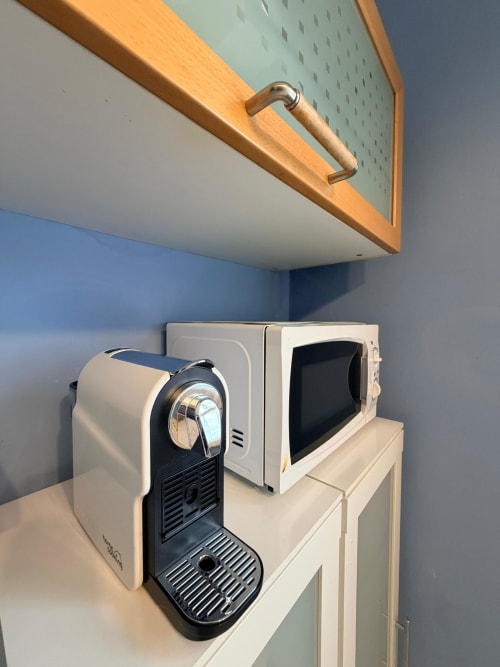 Kitchen corner at Cinelli Apartment Vercelli with espresso machine and microwave under wooden cupboard