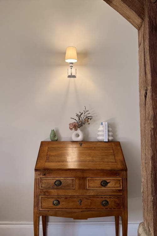 Wooden secretary desk with white wall-mounted lamp and decorative items at La Maison 1680, Couches