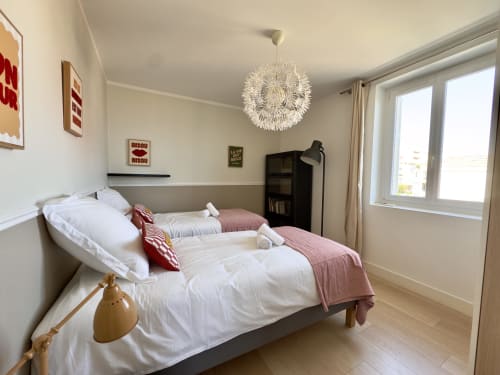 Chambre spacieuse de l'appartement T4 Eugénie de SoleMare, Alata, avec deux lits, draps blancs, plaids roses, suspension et vue mer