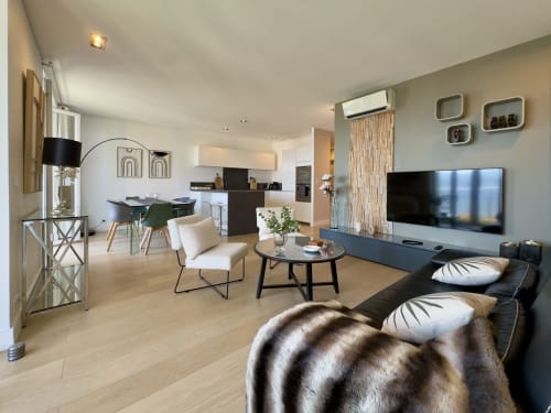 Salon moderne avec vue sur la mer, canapé noir, salle à manger et cuisine ouverte à SoleMare Alata