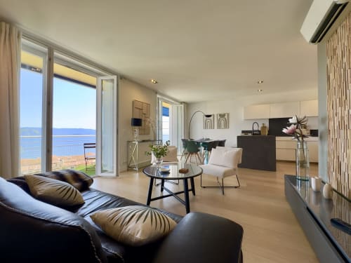 Appartement Eugénie T4 à SoleMare à Alata avec vue mer, salon moderne avec canapé noir, coin repas et balcon côtier