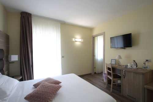 Modern hotel room at Il Viottolo in Roccaraso with queen bed, flat-screen TV, work desk, and balcony access
