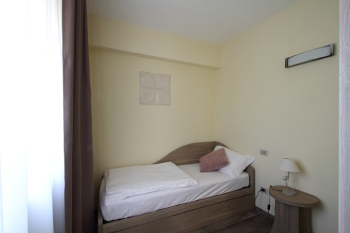 Cozy bedroom at Il Viottolo B&B in Roccaraso with wood bed, white linens, pink cushion, yellow walls, bedside lamp and