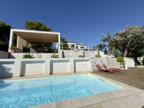 La piscine chauffée avec jacuzzi de VillaSerenita, transats et villa blanche moderne vue jardin à Alata