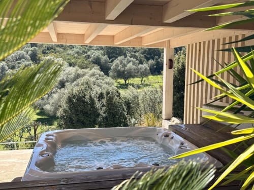Bain à remous SoleMare surplombant les oliveraies d'Alata en Corse, avec pergola en bois et plantes tropicales