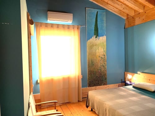 Dormitorio luminoso con paredes azules, vigas de madera y cuadros de cipreses en Casale Artemisia, Capalbio, Toscana