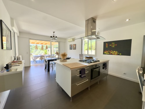 Cuisine contemporaine de l'hôtel SoleMare à Alata avec îlot central, appareils inox et vue sur la terrasse