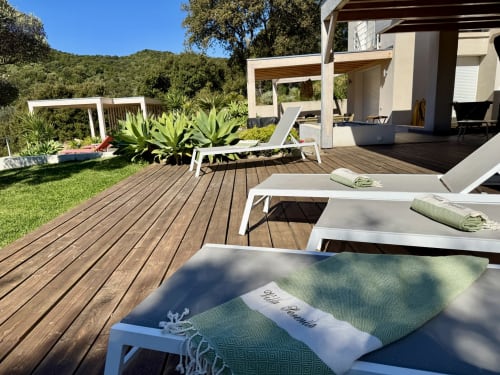 Terrasse SoleMare luxueuse à Alata avec chaises longues, pergola, jardins paysagers et vue sur les collines