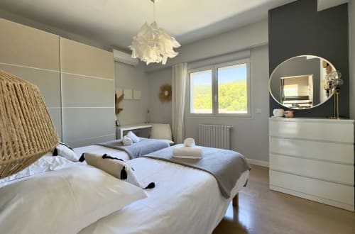 Chambre d'hôtel SoleMare à Alata avec lits jumeaux, mobilier moderne, miroir rond et vue panoramique sur la vallée