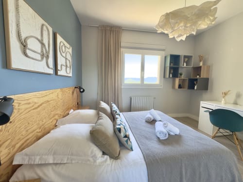 Chambre SoleMare moderne à Alata avec tête de lit en bois, baies vitrées vue mer, décoration murale et mobilier contemporain