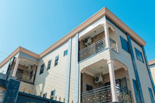 Appart Hotel Kylian à Brazzaville : façade moderne en pierre blanche avec balcons, climatiseurs et ornements métalliques