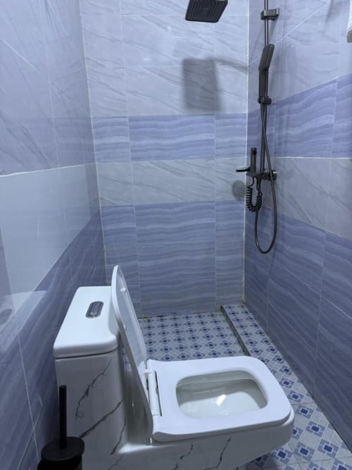 Salle de bains moderne avec toilettes, bidet et douche à l'italienne aux murs carrelés bleus à l'Appart Hôtel Kylian, Brazzaville