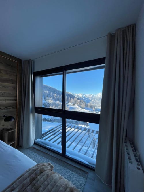 Chambre moderne du chalet CIRELINE Risoul avec baie panoramique vue sur les montagnes alpines enneigées