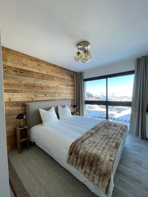 Chambre moderne du chalet de Risoul avec tête de lit en bois, literie blanche et vue panoramique sur les montagnes