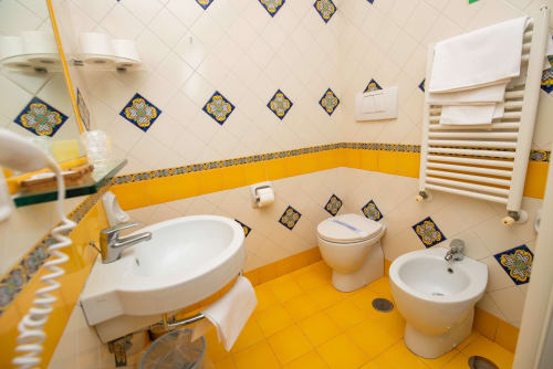 Luminoso bagno con piastrelle gialle, due lavabi, toilet e bidet a Casa Mannini B&B a Maiori, Italia