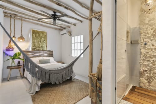 Beachfront cottage bedroom at Isla Mujeres with hammock, wooden beams, and ocean view through windows