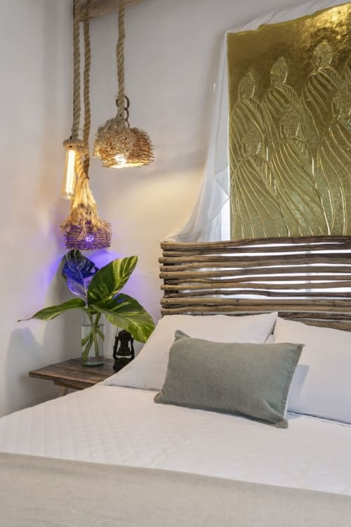 Beachfront bedroom at Casa Amor, Isla Mujeres with hanging rope lights, blue flower plant, wooden headboard, and ocean view