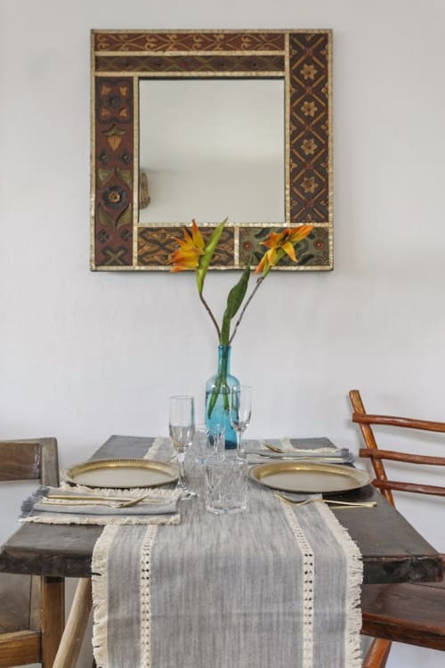 Elegant dining setup at Casa Amor with ornate mirror, yellow flowers, and table settings overlooking Isla Mujeres