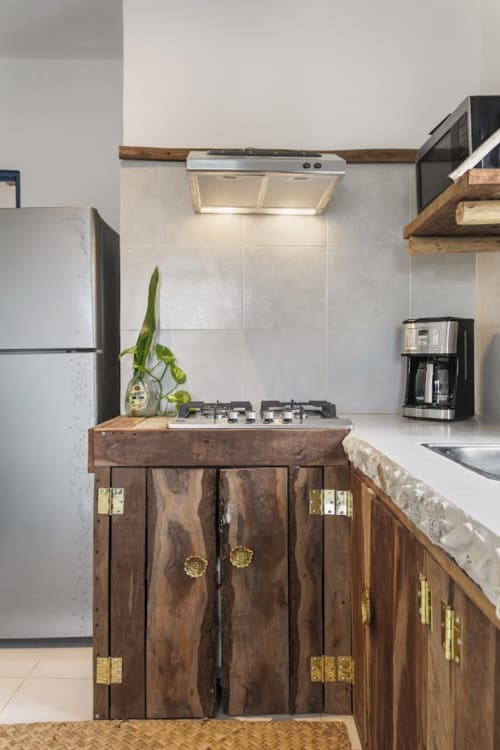 Modern kitchen with rustic wooden cabinets, gas stovetop, and white tile backsplash at Casa Amor Ocean Front cottage in Isla