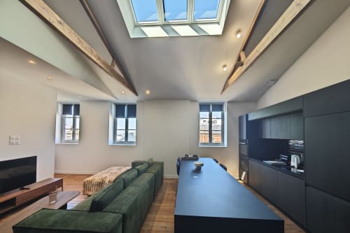 Suite loft moderne à l'hôtel O LIT en France avec puits de lumière, canapé vert, cuisine noire et parquet