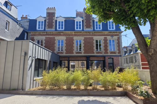 Cour de l'hôtel O LIT en France avec façade en brique, toit mansardé bleu et extension moderne au rez-de-chaussée entourée de