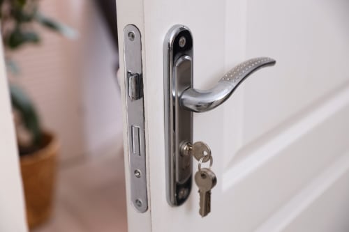 Poignée de porte chromée moderne avec serrure et clés sur porte blanche à l'hôtel O LIT en France
