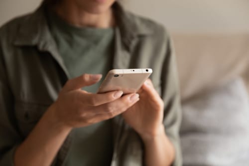 Personne tenant un smartphone à l'hôtel O LIT, consultant les services numériques