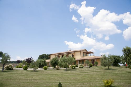 Villa toscane à l'Agriturismo Buriano de Lubriano avec façade en terre cuite, jardins soignés, oliviers et ciel bleu