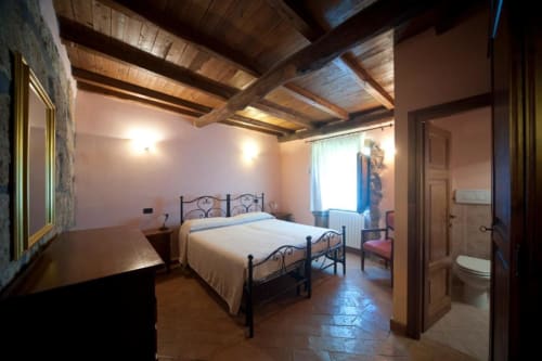 Camera ampia dell'appartamento La Quercia ad Agriturismo Buriano, Lubriano, con letto in ferro battuto, travi in legno e bagno privato