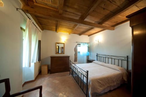Camera da letto spaziosa in Agriturismo Buriano a Lubriano, con letto in ferro battuto e travi in legno