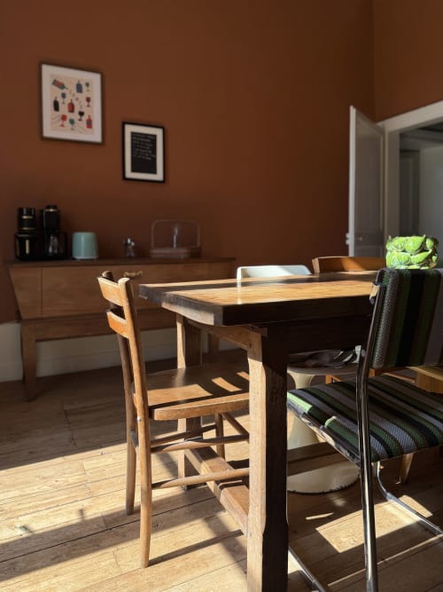 Salle à manger rustique à la Maison Mansel avec table en bois, chaises vintage et murs en terre cuite chaleureuse