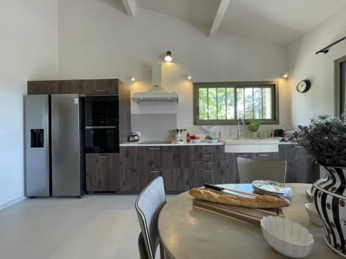 Moderne Küche und Speisebereich mit dunklen Schränken, Edelstahlgeräten und Gartenblick im Cottage von Gordes.