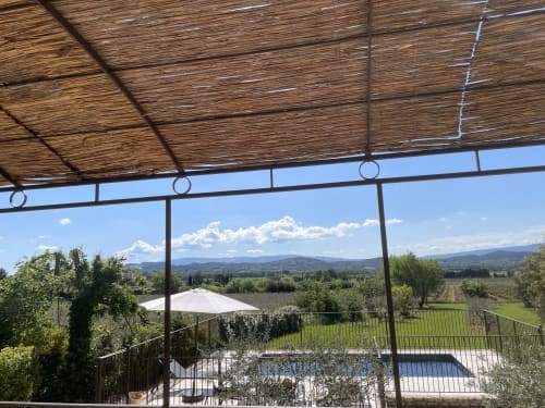 Terrasse ombragée avec vue sur la piscine surplombant les vignobles et les montagnes de Gordes, Provence
