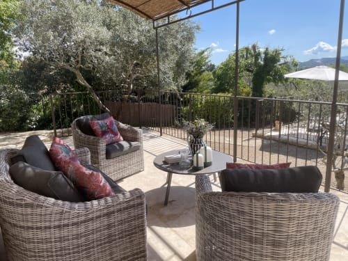 Sonnige Terrasse des Ferienhauses Joucas mit Korbmöbeln, Olivenbäumen und Blick auf die provenzalische Landschaft bei Gordes
