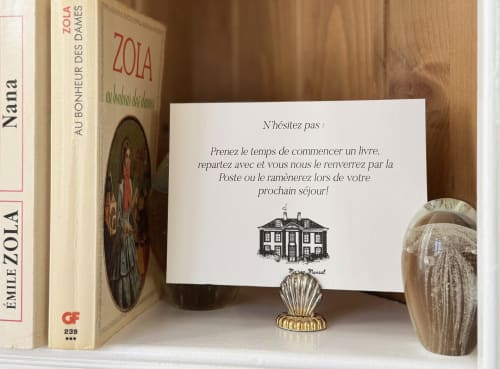 Bibliothèque de la Maison Mansel affichant des livres français et une carte de bienvenue invitant les hôtes à la propriété du Mesnil-en-Ouche