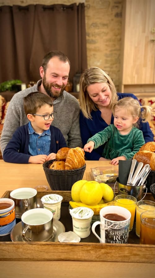 Family enjoying breakfast with croissants and fruit at Le Clos Des Anges B&B in Bagnols, France