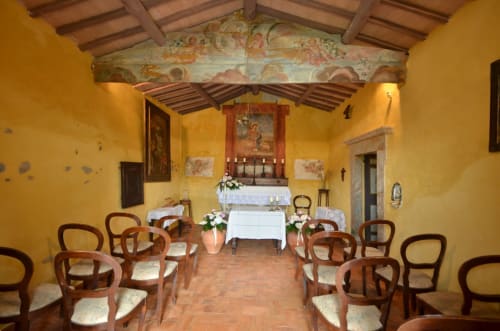 Kapellenraum im Agriturismo Buriano in Lubriano mit gelben Wänden, Holzbalken, Altar und Holzstühlen