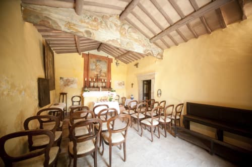 Kapelle Agriturismo Buriano in Lubriano mit Holzstühlen, gelben Wänden und sichtbaren Balkendecke für intime Zusammenkünfte.