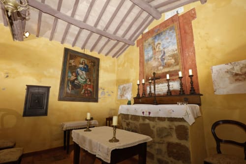 Rustikale Kapellenräume im Agriturismo Buriano mit gelben Wänden, religiöser Kunst, Altar und kerzenbeleuchtetem Mobiliar in Lubriano