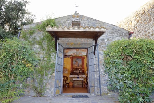 Steinkapelle am Agriturismo Buriano in Lubriano, Italien, mit Holztüren und Kreuz auf dem Dach