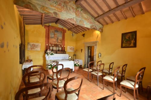 Helles Kapelleninterieur im Agriturismo Buriano mit Holzstühlen, Altar und Freskendecke in Lubriano