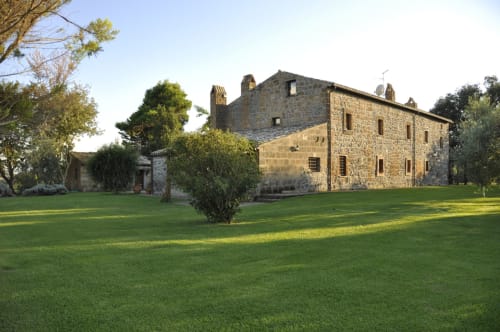 Agriturismo Buriano - Steinvilla in Lubriano mit grünen Rasenflächen und Baumbestand bei Sonnenuntergang