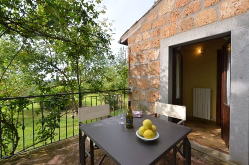 Terrasse des Agriturismo Buriano in Lubriano mit Esstisch, Wein, Zitronen und Landblick