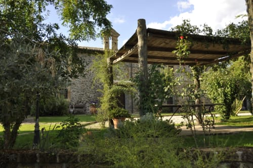 Garten des Agriturismo Buriano mit Steingebäude, Holzpergola und üppigem Grün in Lubriano, Italien