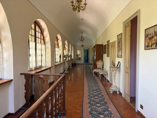 Lungo elegante corridoio con finestre ad arco, balaustre in legno e arredi d'epoca presso la Villa Mirano B&B a Piossasco