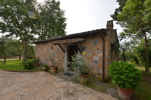 Rustikales Steinhaus in der Agriturismo Buriano in Lubriano, Italien, umgeben von Bäumen und Topfpflanzen