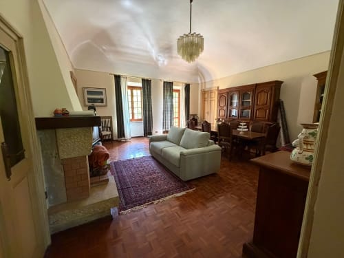 Ampio soggiorno della Villa Mirano con camino, divano color crema, zona pranzo e arredi eleganti a Piossasco